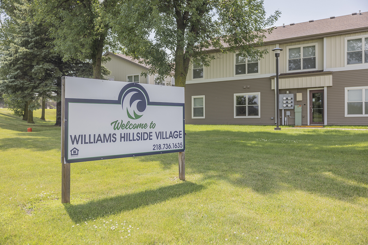 A sign outside an apartment building reads welcome to Hillside Village