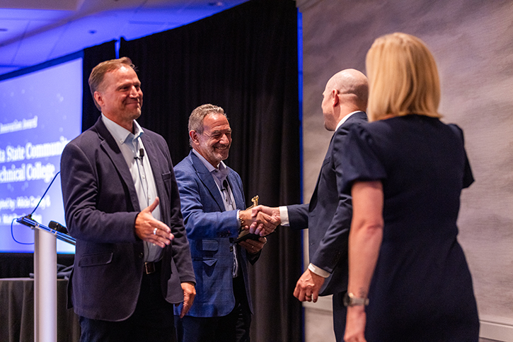 Two Coursedog leaders shake hands with two M State representatives on stage at the 2025 awards ceremony.