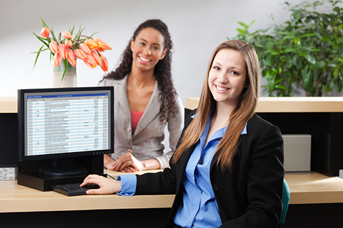 two people stand next to a computer