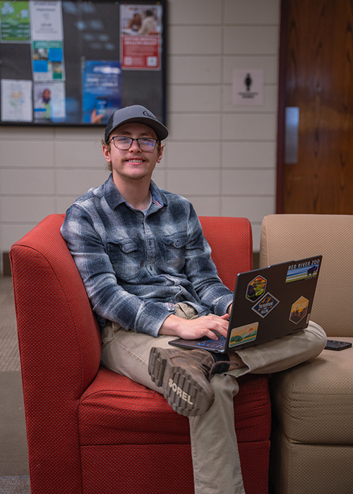 An M State student works on a laptop in a commons area