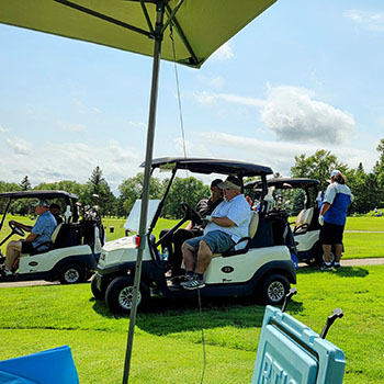 Golfers in a cart drive across a course