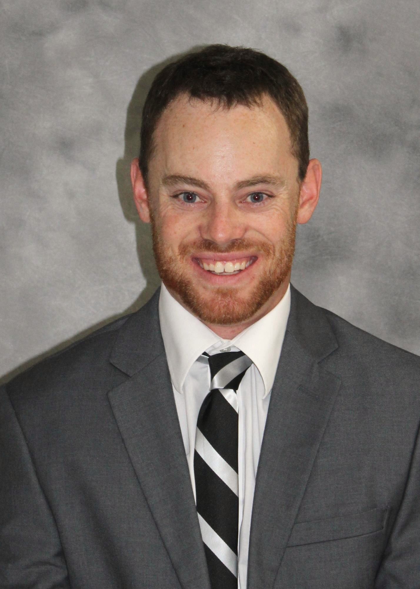 Dalton Parks, M State's new head baseball coach, wearing a suit and tie and smiling into the camera