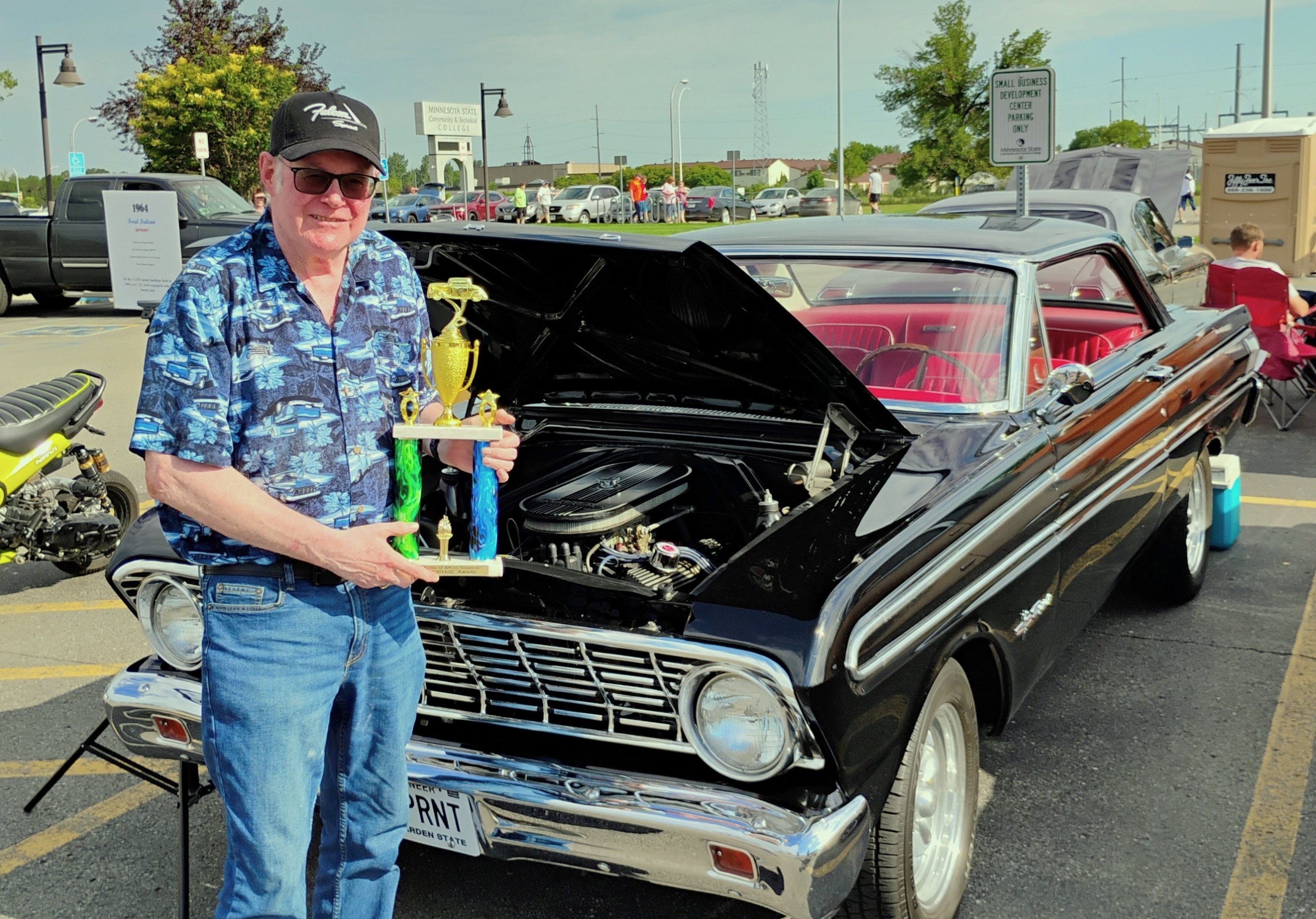 Robert Berry, the first-ever winner of the M State School of Applied Technology’s Auto Heritage Award, poses with his trophy in front of his winning 1964 Ford Falcon Sprint at the May 2025 Cruise Night event at the college’s Moorhead campus.