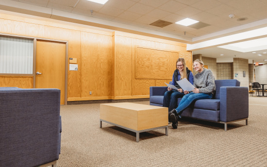 Two girls sitting on a couch in the student commons