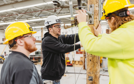 Three electrical line worker students are practicing skills in the classroom