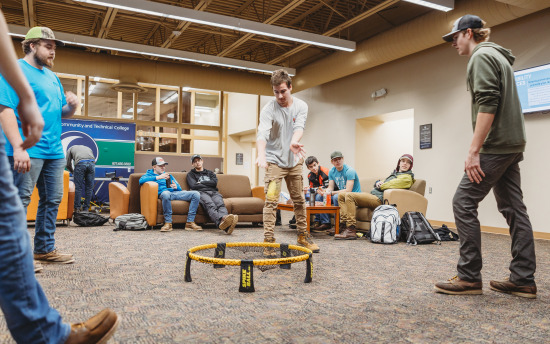 several students are hanging out in the student commons playing spike ball