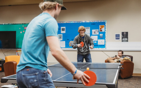 two students playing ping pong in the student commons