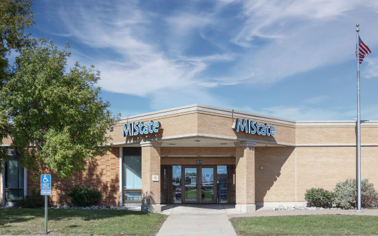 The front of the M State-Detroit Lakes Building that showcases the brick building, large, welcoming doors and an M State sign