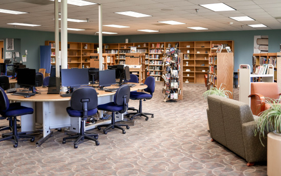 A photo of the library featuring a table full of desktop computers and many bookshelves