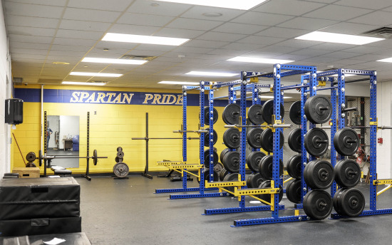 a gym with weights and equipment in the middle of the room with "Spartan Pride" painted on the back wall