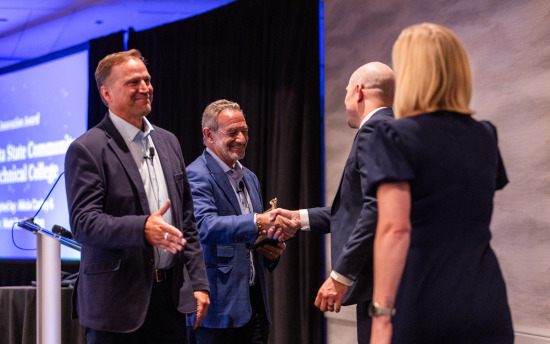 Coursedog leaders shake hands with two M State representatives at the 2025 Coursedog awards ceremony in Chicago.