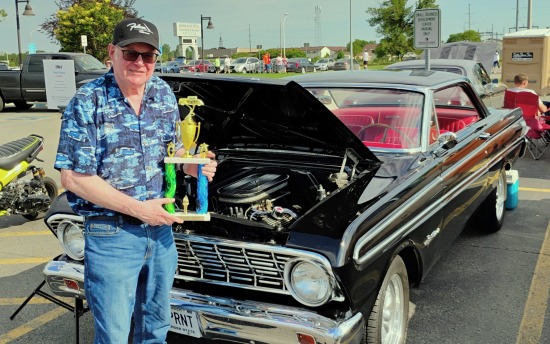 Robert Berry, the first-ever winner of the M State School of Applied Technology’s Auto Heritage Award, poses with his trophy in front of his winning 1964 Ford Falcon Sprint at the May 2025 Cruise Night event at the college’s Moorhead campus.