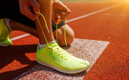 A person tying their athletic shoe on a track