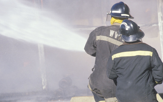 Firefighters spray water on a fire