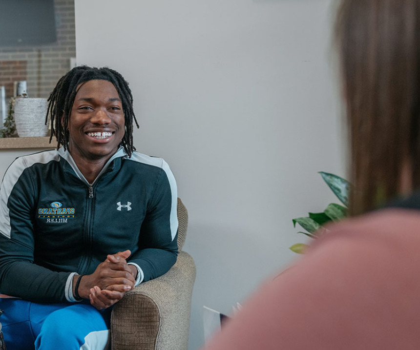 A smiling student sits in an office