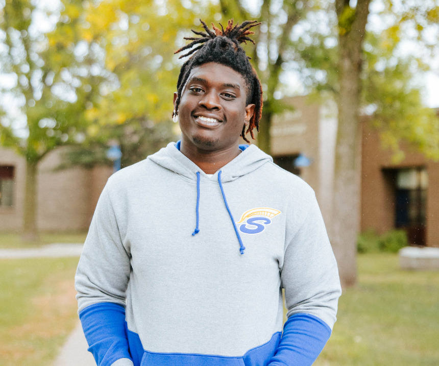 Fergus Falls student smile infront of campus building.