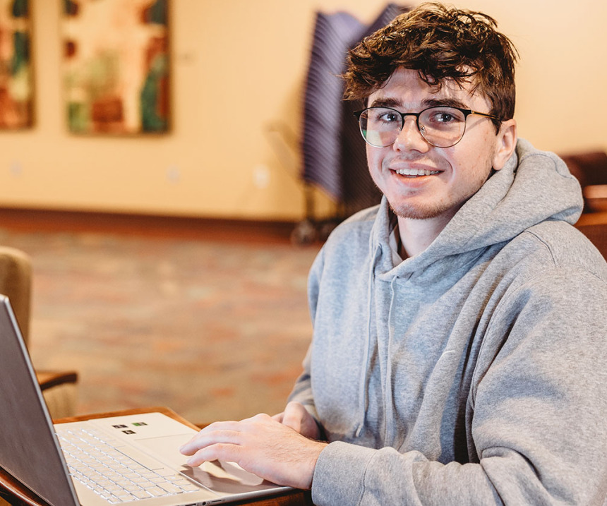 A student looks up from a laptop