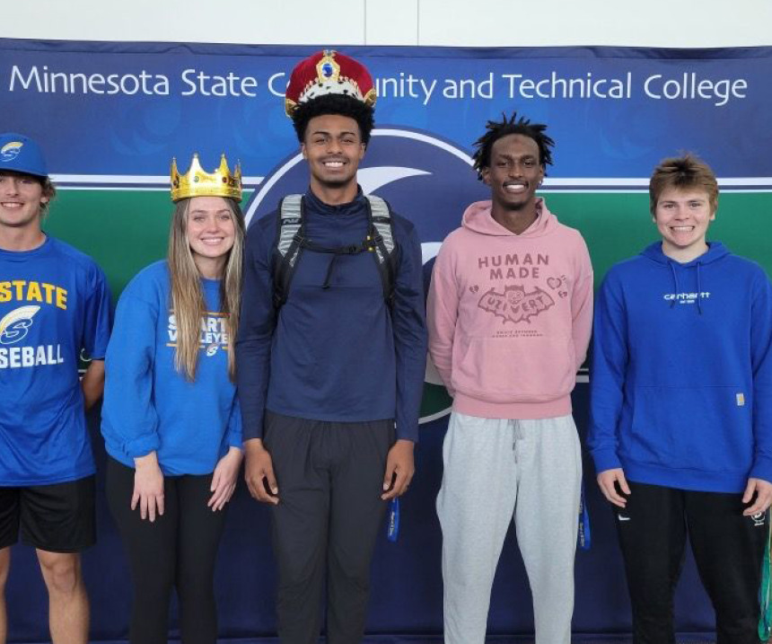 M State homecoming royalty stand in front of the M State logo