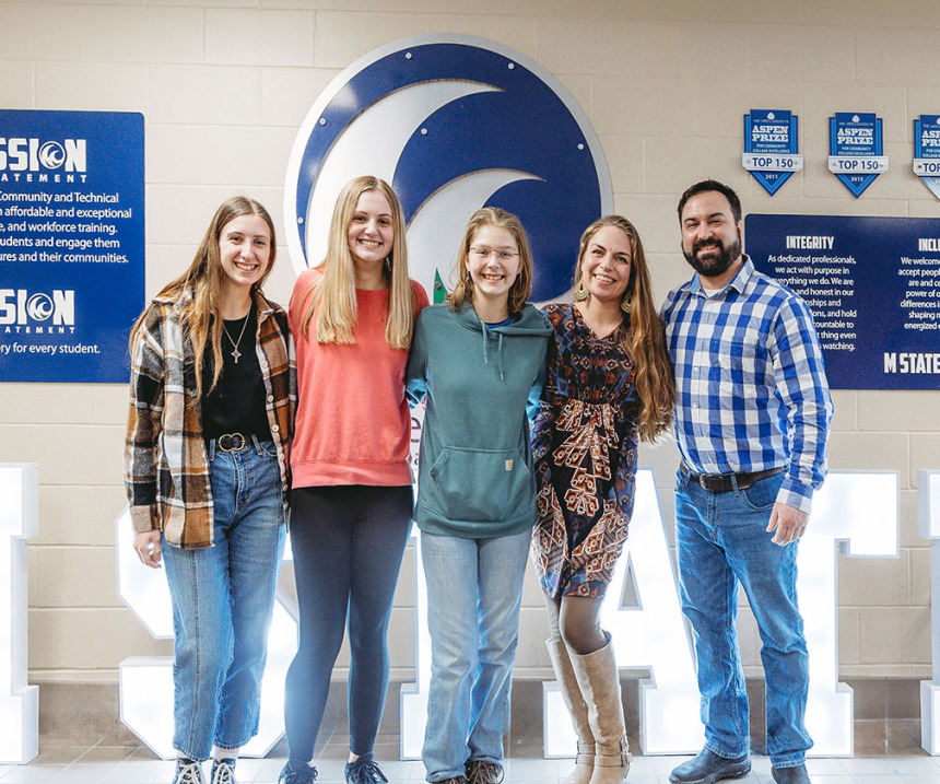 Students stand in front of the M State logo at the Detroit Lakes campus