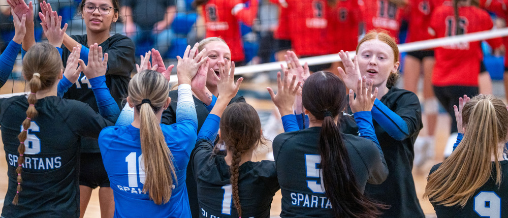 M State Spartans volleyball players high five by the net
