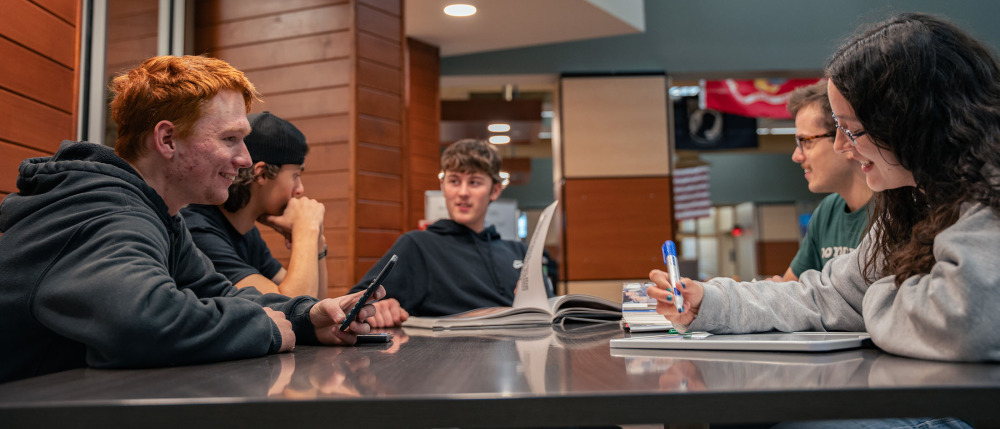 Students sit at a table near an M State library