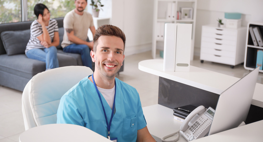 A medical employee looks up from working at a computer