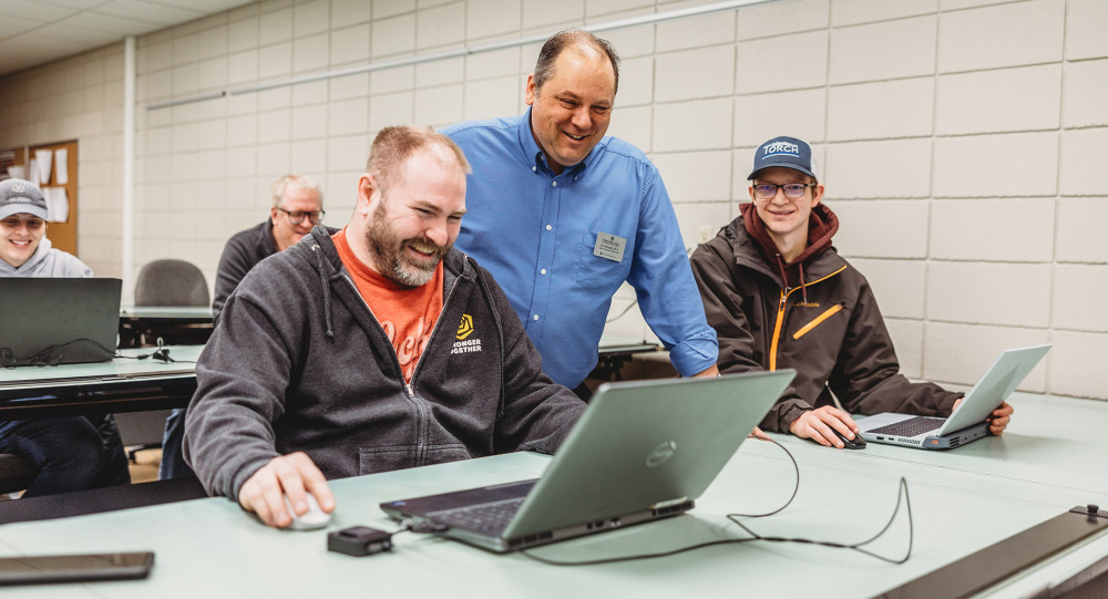 An instructor observes a student on a laptop