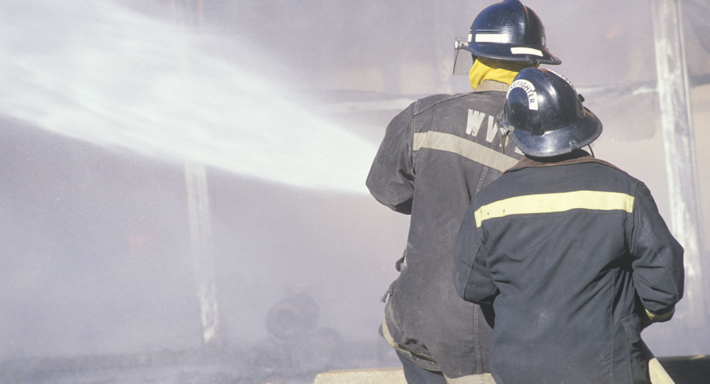 Firefighters spray water on a fire