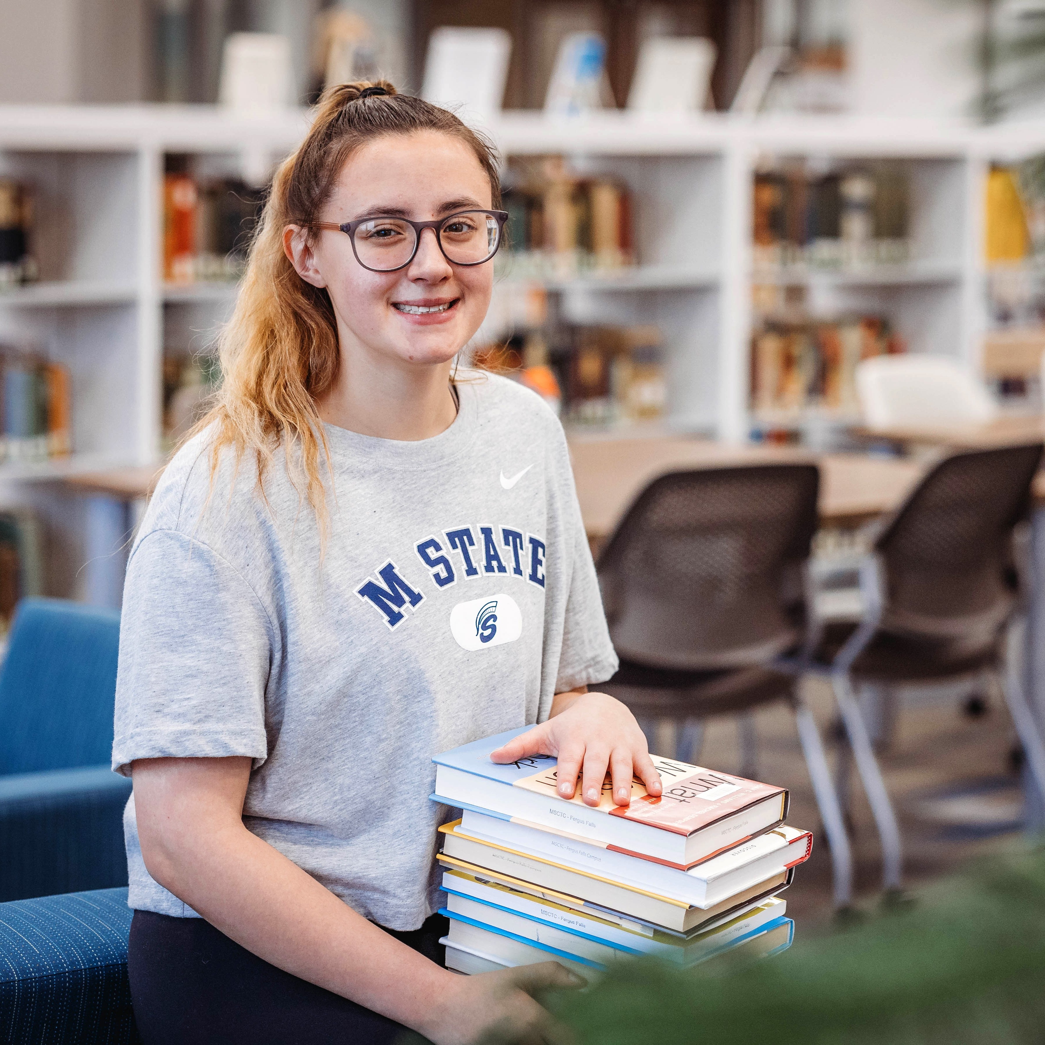 An M State student on the Fergus Falls campus checks out a stack of books from the campus library.