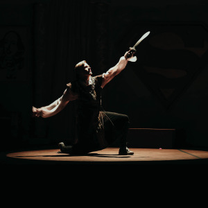 An M State actor holds a sword into the spotlight on the Waage Theatre stage
