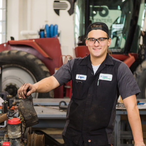 A student poses in front of a tractor inside Moorhead's Diesel Equipment Technology lab